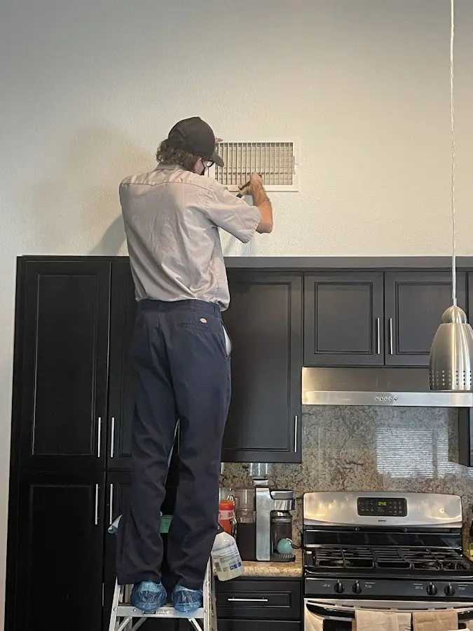 Technician inspecting an air vent during HVAC service in Latrobe
